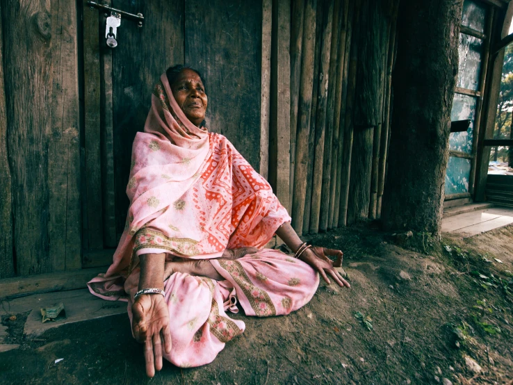 an old lady sitting by a door with her hands folded out