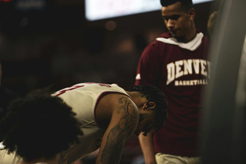 the coach has a maroon uniform on and is touching his head