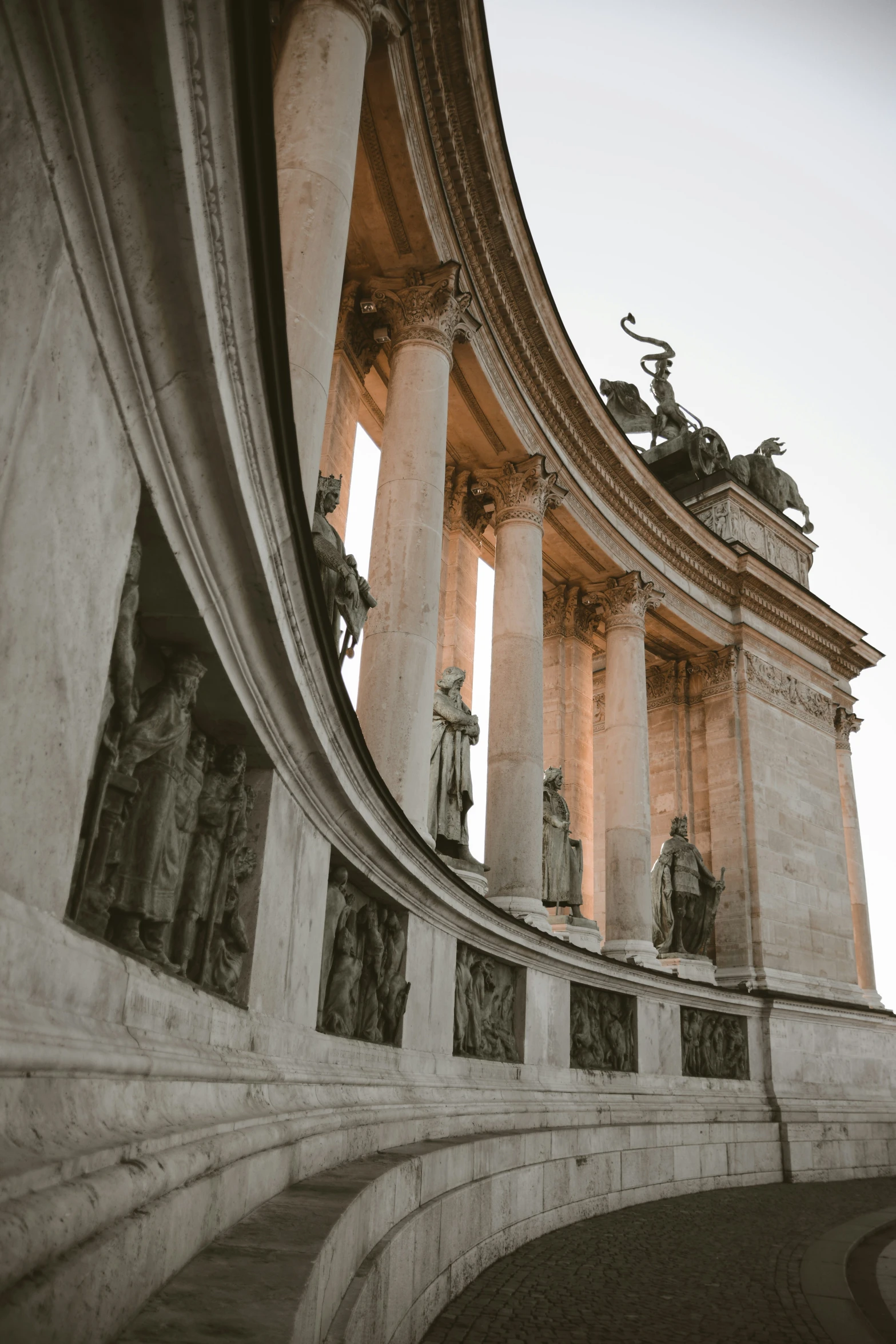 several statues at the top of an archway and a building with columns