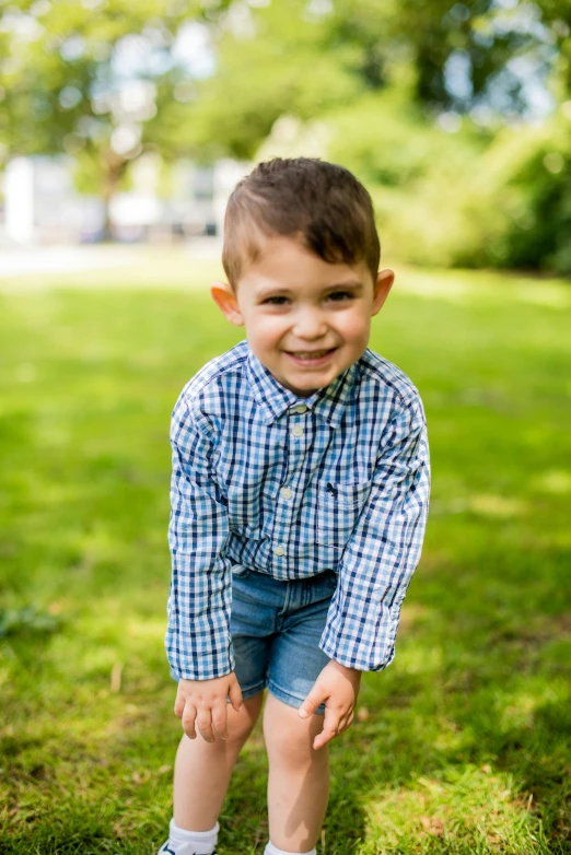 a boy in blue shorts and checkered shirt posing for a picture