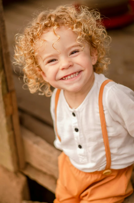 a  is wearing overalls smiling at the camera