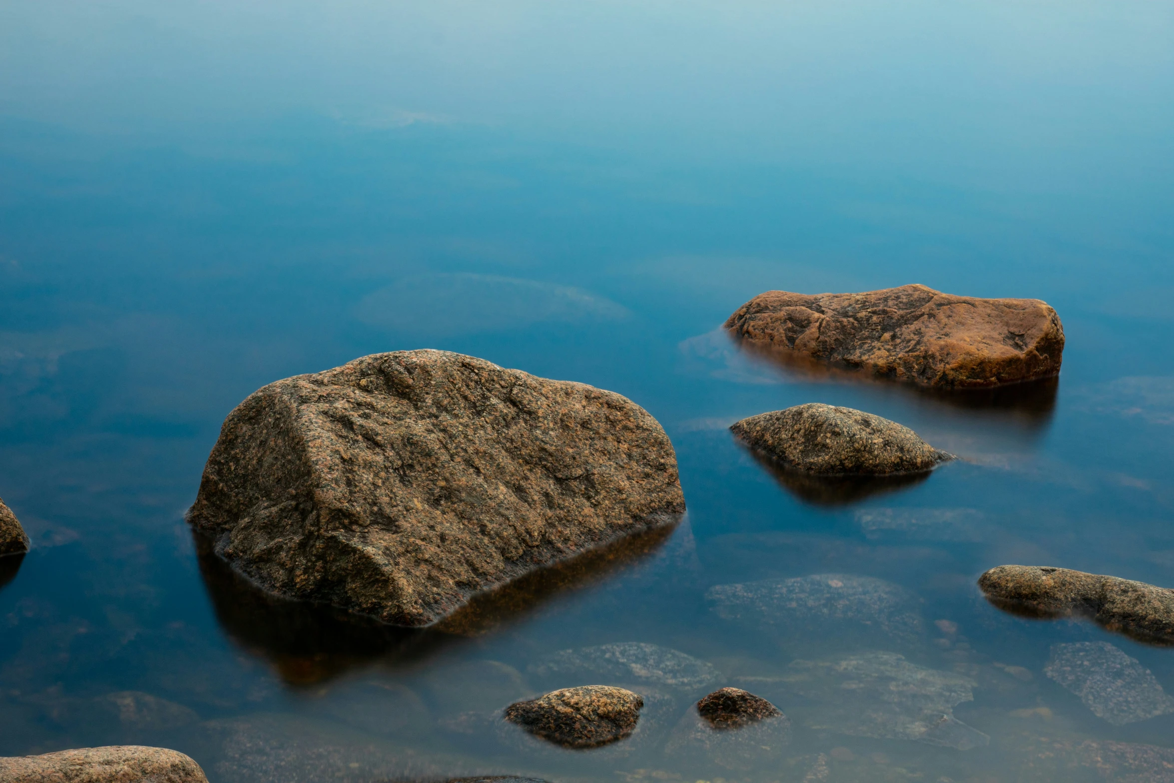 some rocks in the water with their reflections