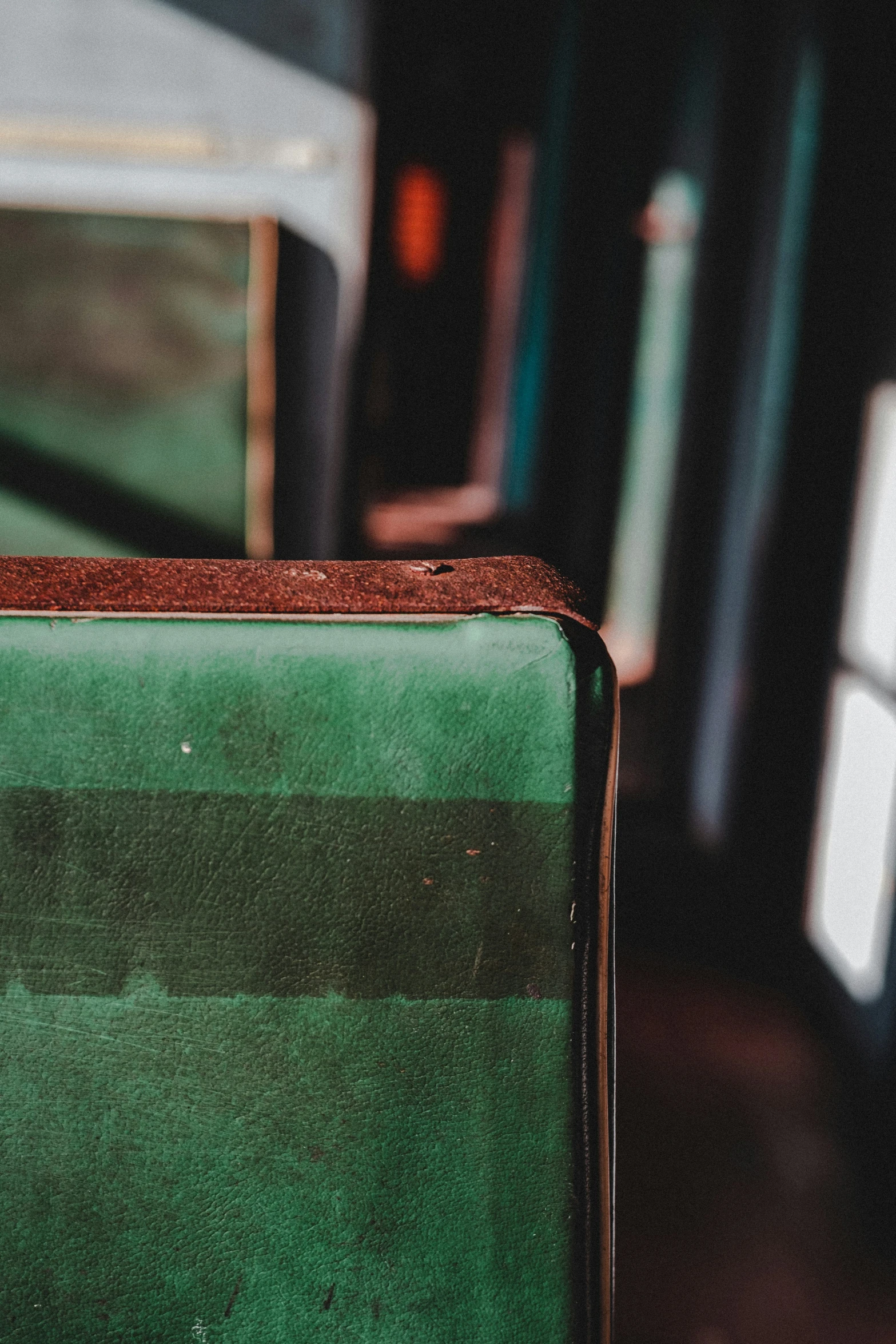 a luggage bag with green stripes next to a chair