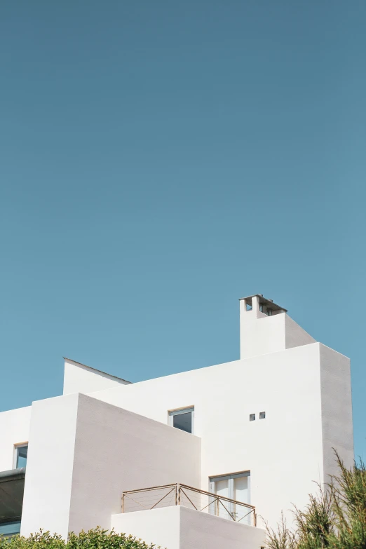 a tall white building sitting next to a lush green field