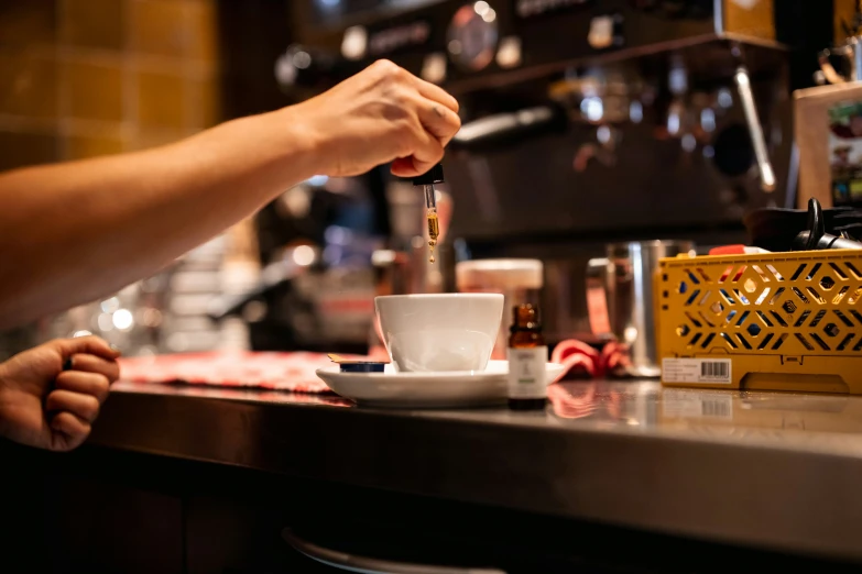 the baristale at the bar is pouring some liquid into the cup