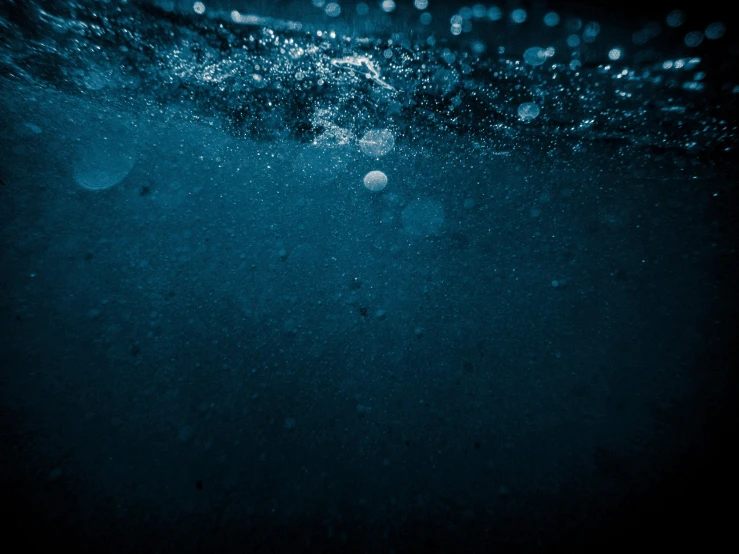 the dark and very blue water has bubbles