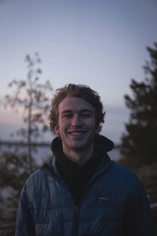 a young man wearing a blue jacket and smiling at the camera