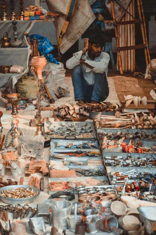 a man sitting at a store with several trays of items on it