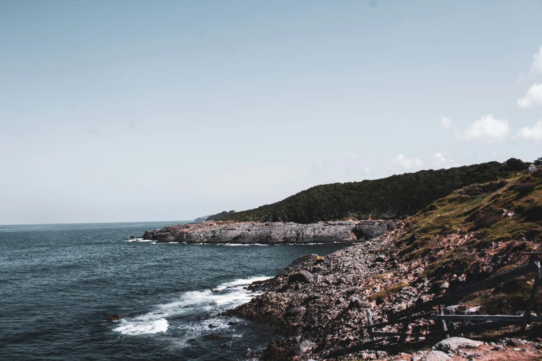 a lone boat floating along the ocean with mountains in the background