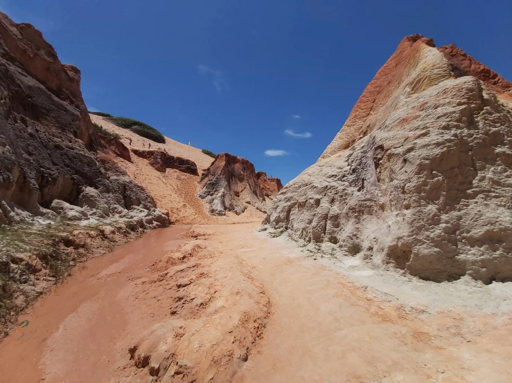 a dirt road between some rocks under a blue sky