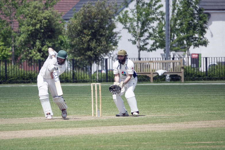 two players in white playing a game of cricket