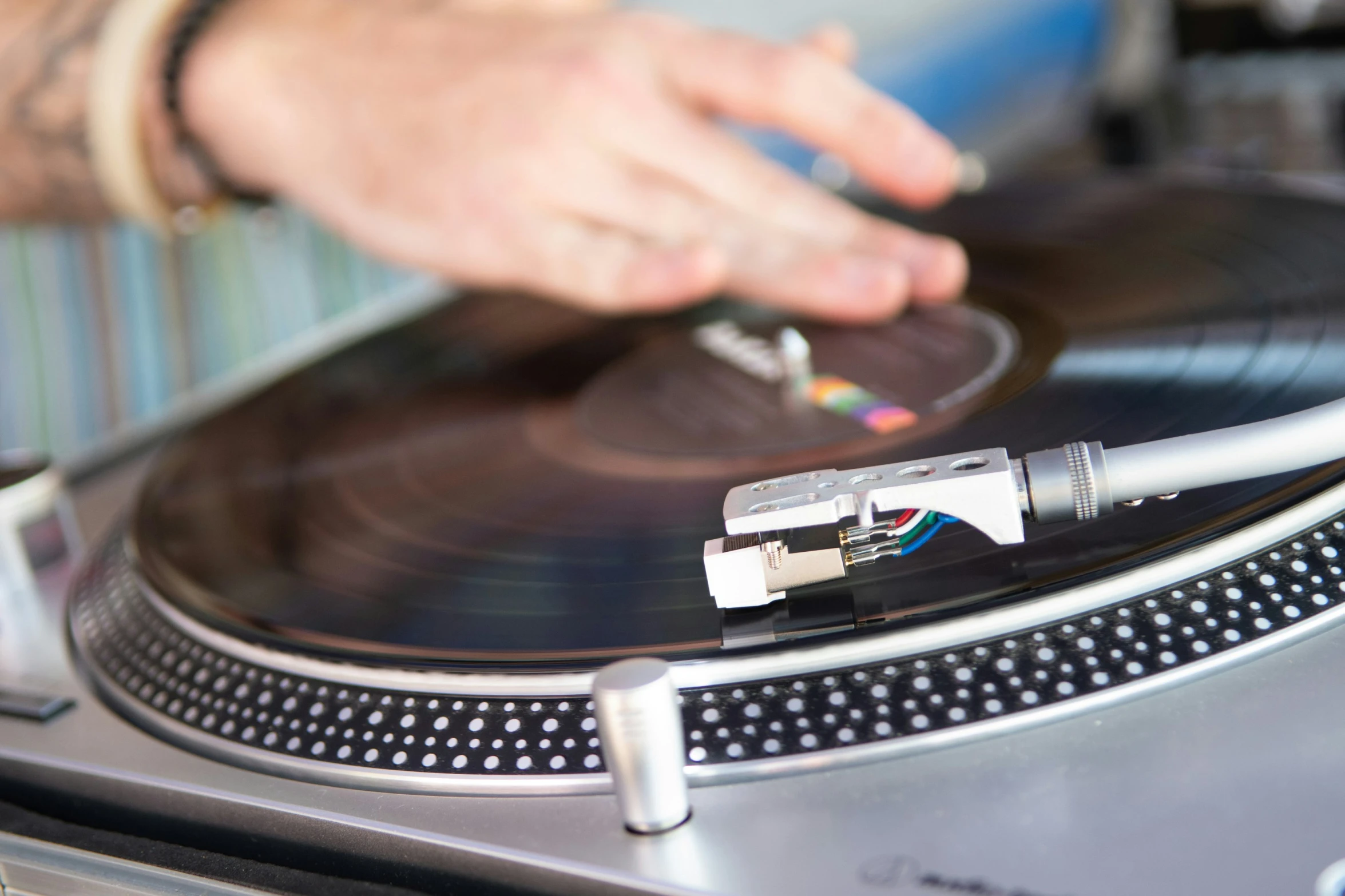 a hand with a record player next to a turntable