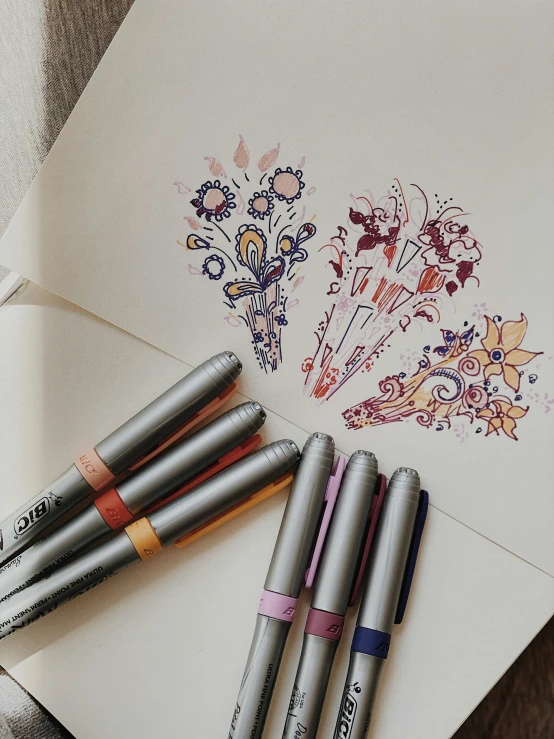 four ink pens sitting on top of a piece of paper