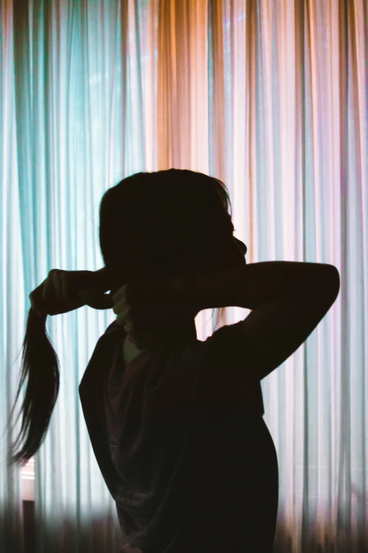 a woman covering her ears while standing in front of curtain