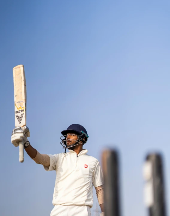 a man is holding his bat up and wearing a helmet