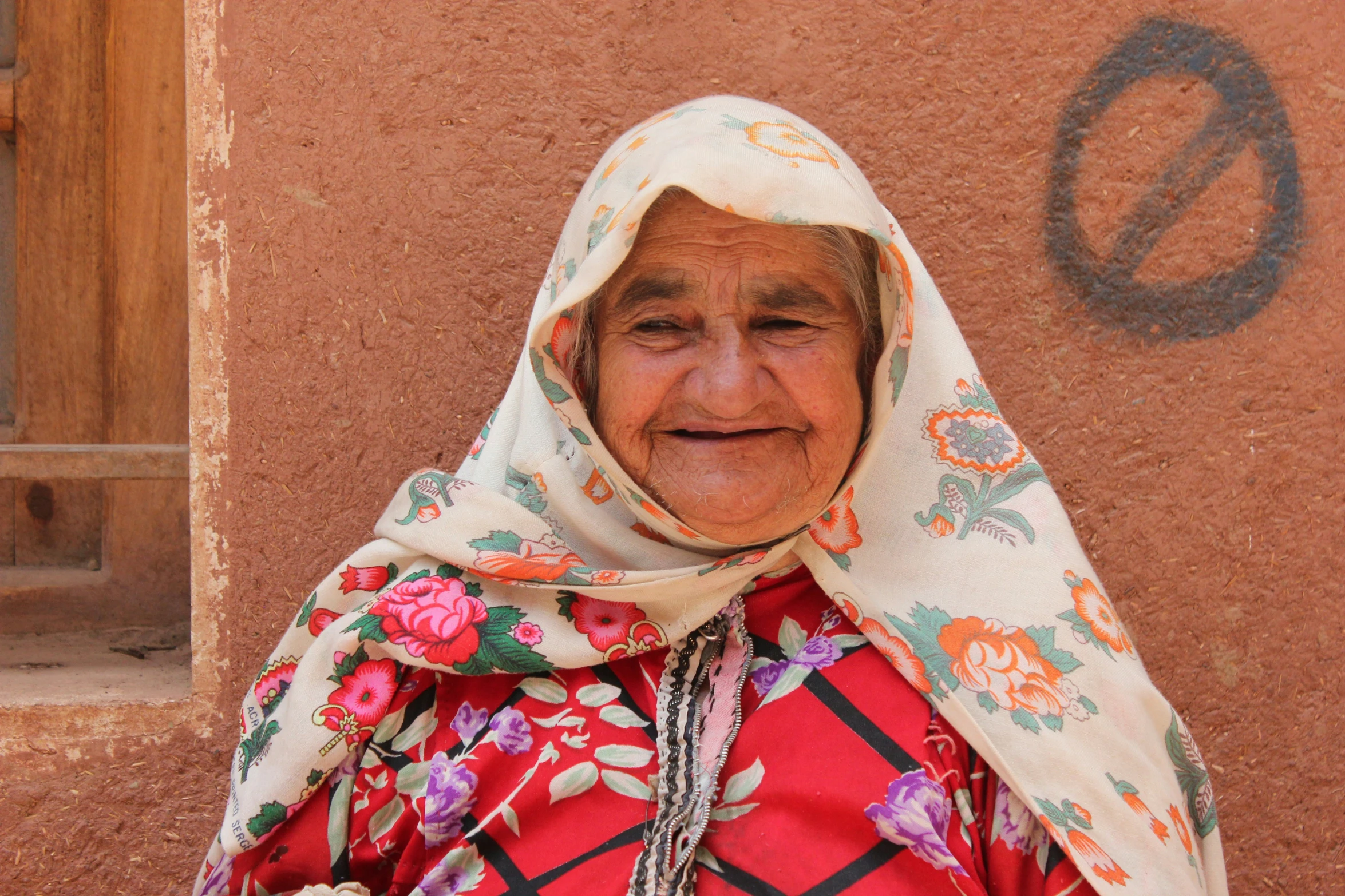 an elderly lady wearing a floral robe is posing for a picture