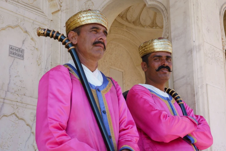 two men with gold colored hats standing in front of a building