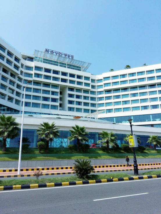 a large building with palm trees and bushes near the side