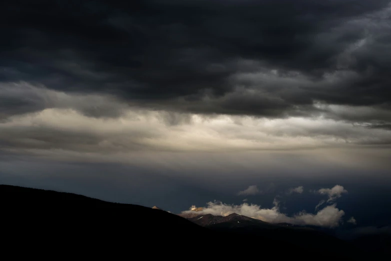 a bird flying in the sky, below a very dark cloudy sky