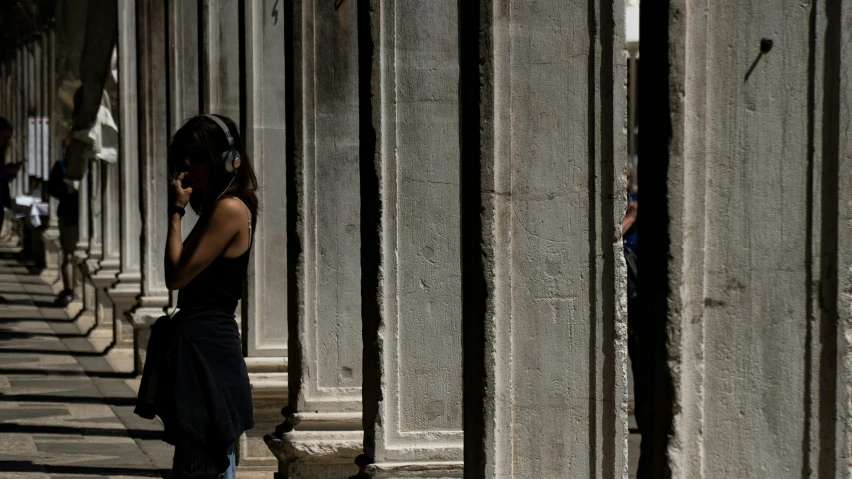 a young woman talks on a cell phone while leaning against pillars