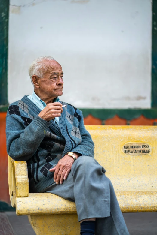 an old man sitting on a yellow bench