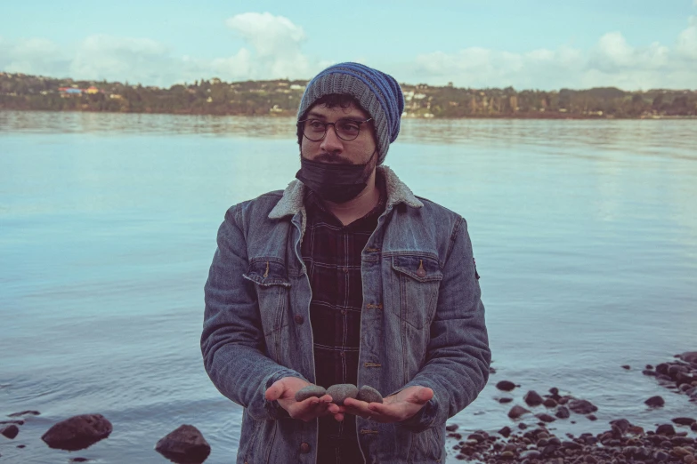 man in plaid jacket standing in front of a body of water