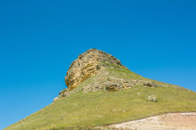 a hill with green grass and a clear blue sky