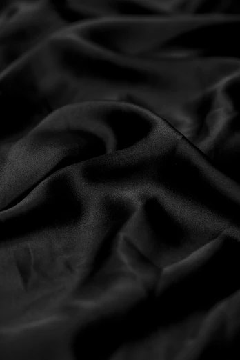 black silk fabric is laid on top of a bed