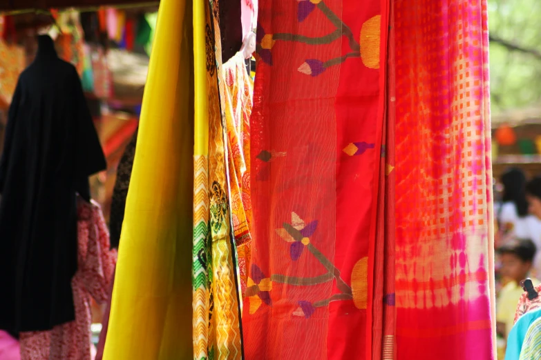 various colorful scarfs on sale next to some people