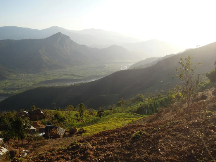 a hillside with grass, dirt and mountains surrounding