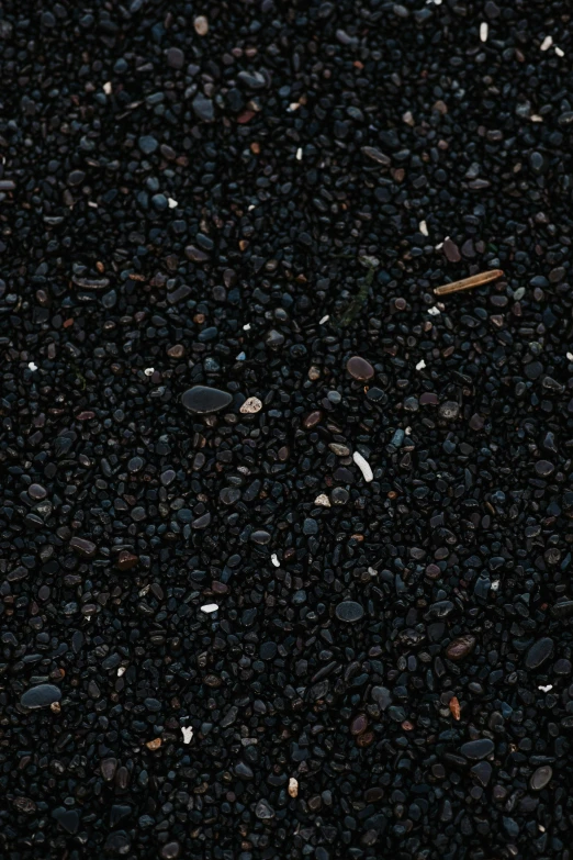 a black textured ground with small stones and a small piece of orange