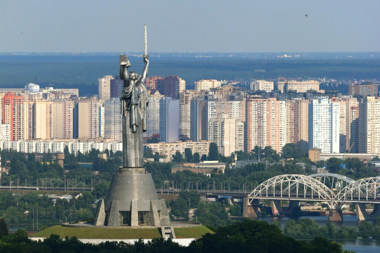 a large statue in front of a city filled with tall buildings