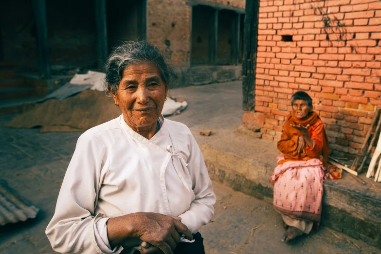 an old woman standing next to a little girl in front of a brick building