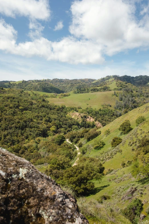 lush green hills with valleys and fields under a cloudy blue sky