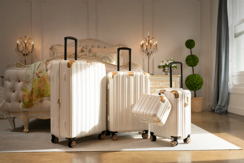 three white suitcases on wheels leaning against a wall