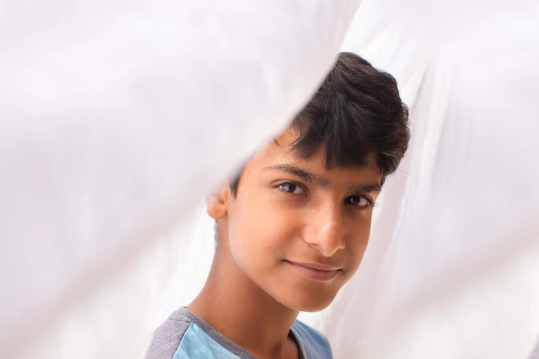 a young man is standing under a white sheet