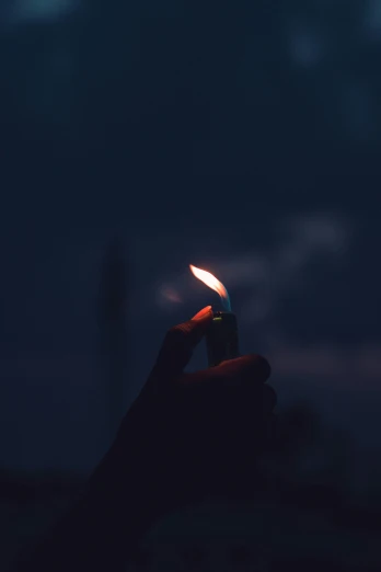 a person's hand holding a lit match candle