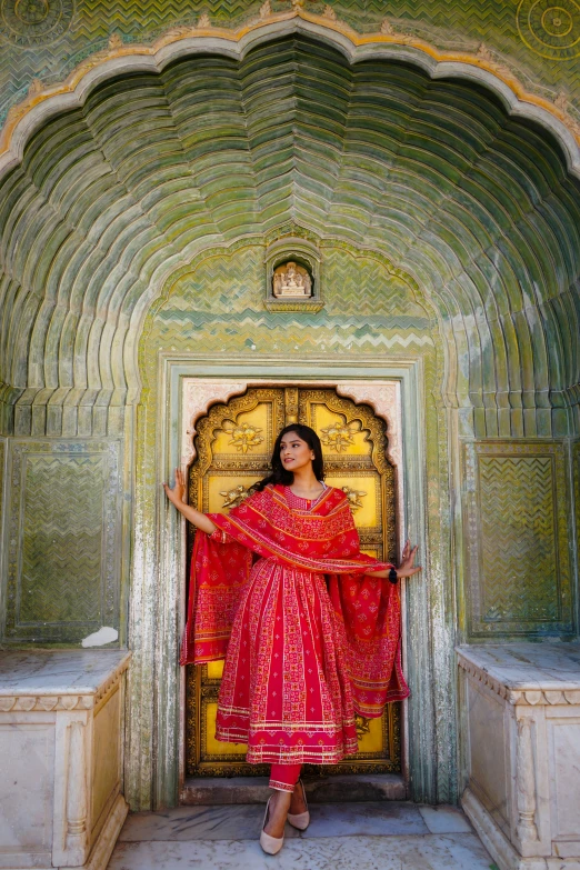 a beautiful woman in red clothes poses with an ornate doorway