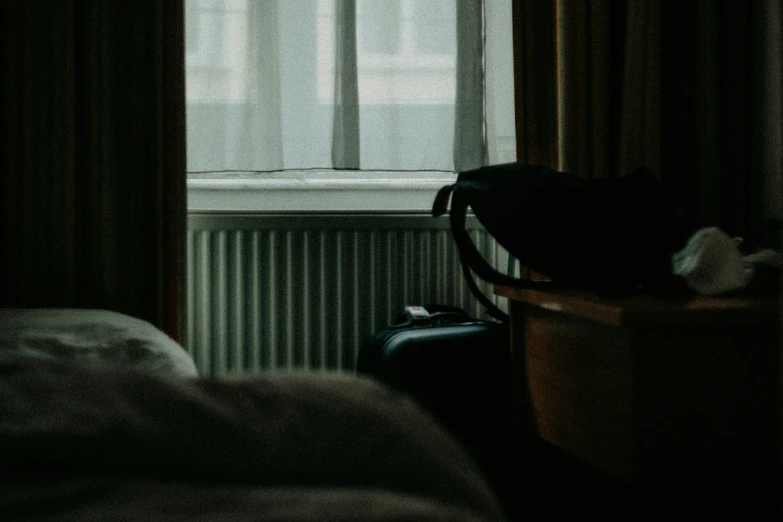 the window in the room is dark, with a luggage bag sitting by it