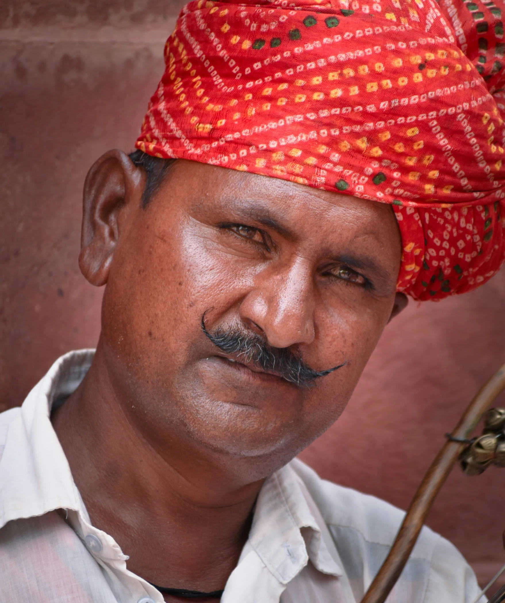 a man with a moustache on, wearing an ornate red turban