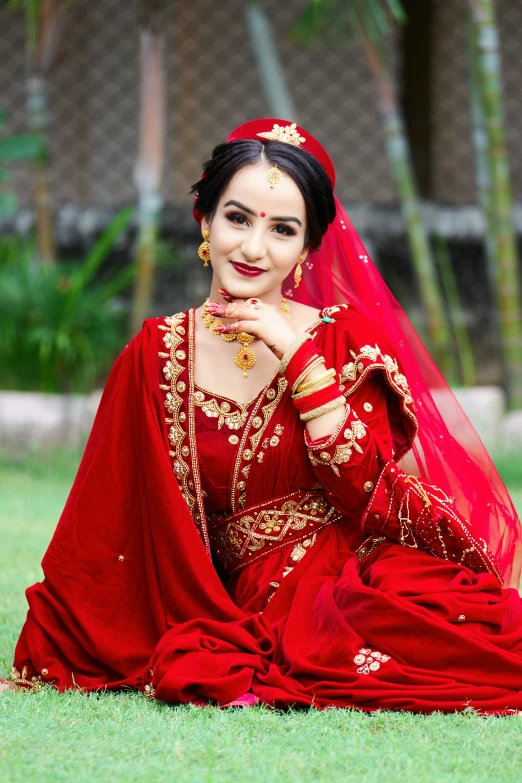 a woman in red and gold sitting on the grass