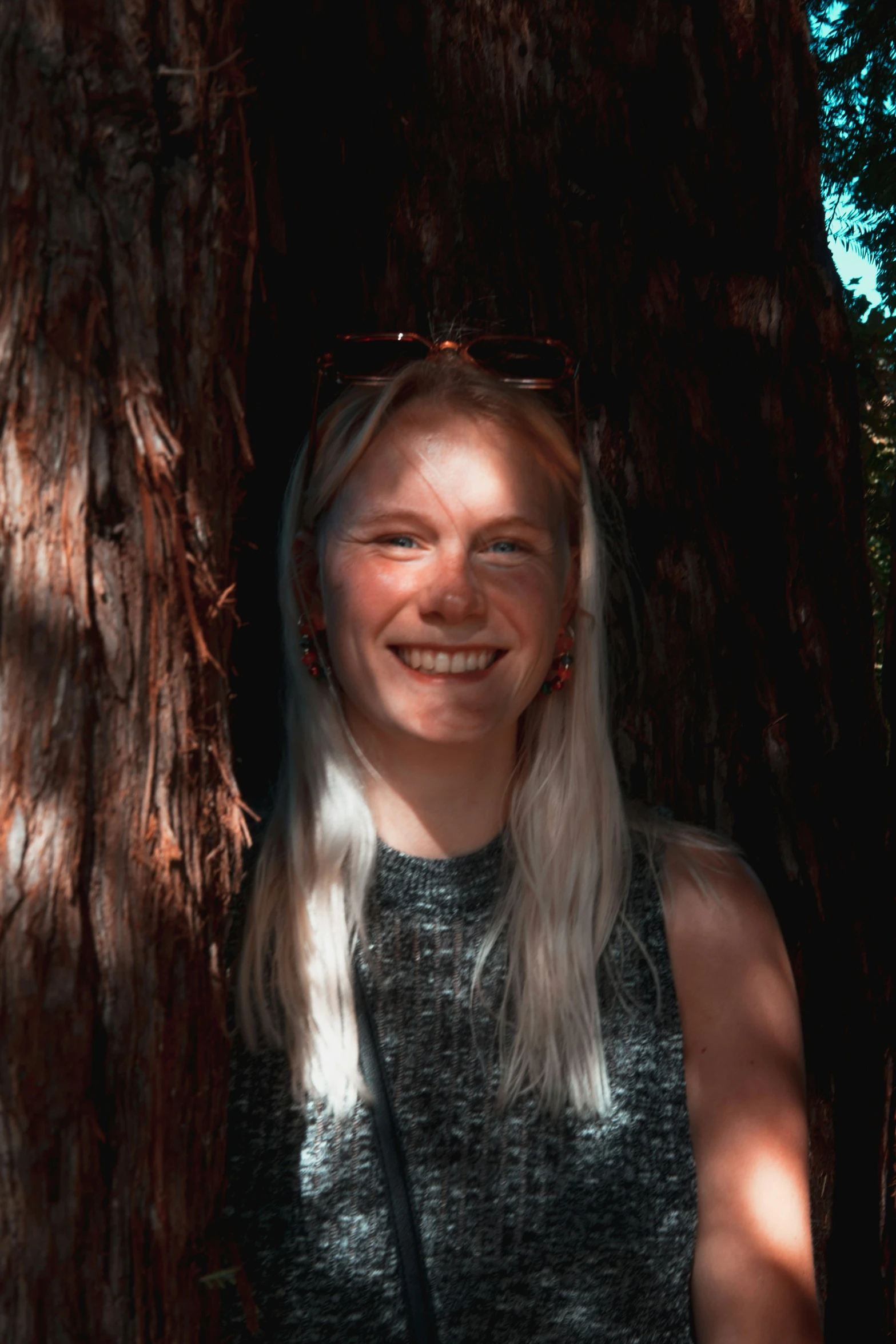 a woman in glasses smiles under the bark of a tree