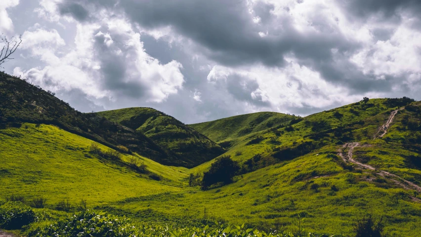 green hills are in the distance while the clouds fly overhead