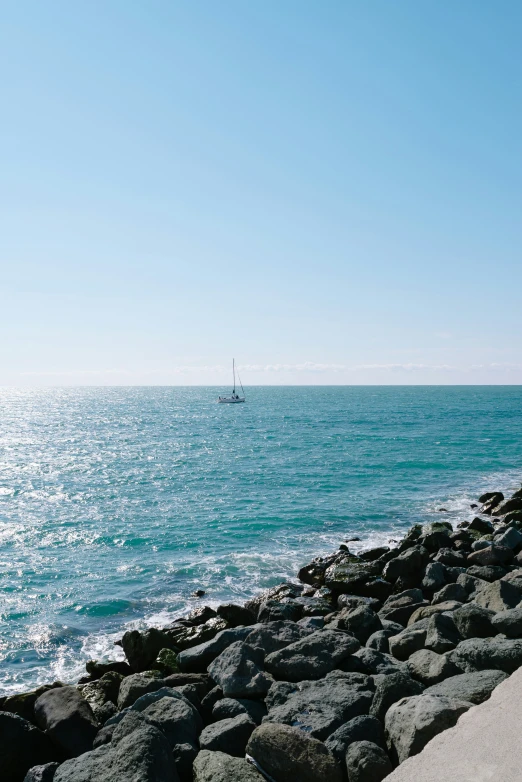 a couple sitting on a rock next to the ocean