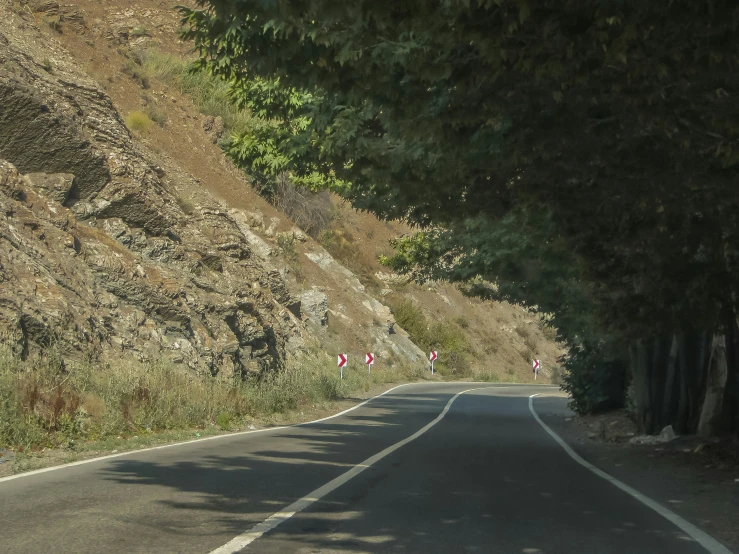 the road is curved in to one direction and has a cliff