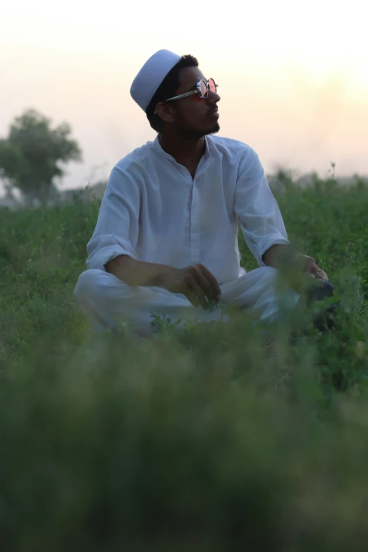 man wearing hat sitting in the middle of tall grass