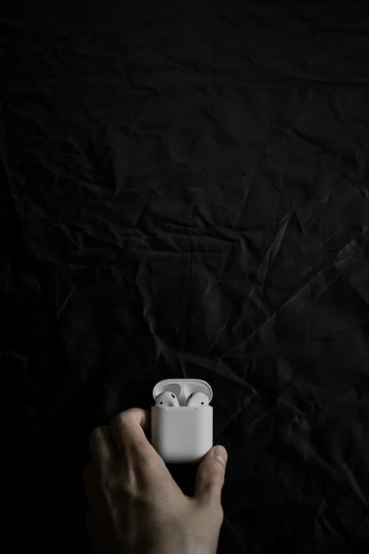 a person holds an airpods in their hand