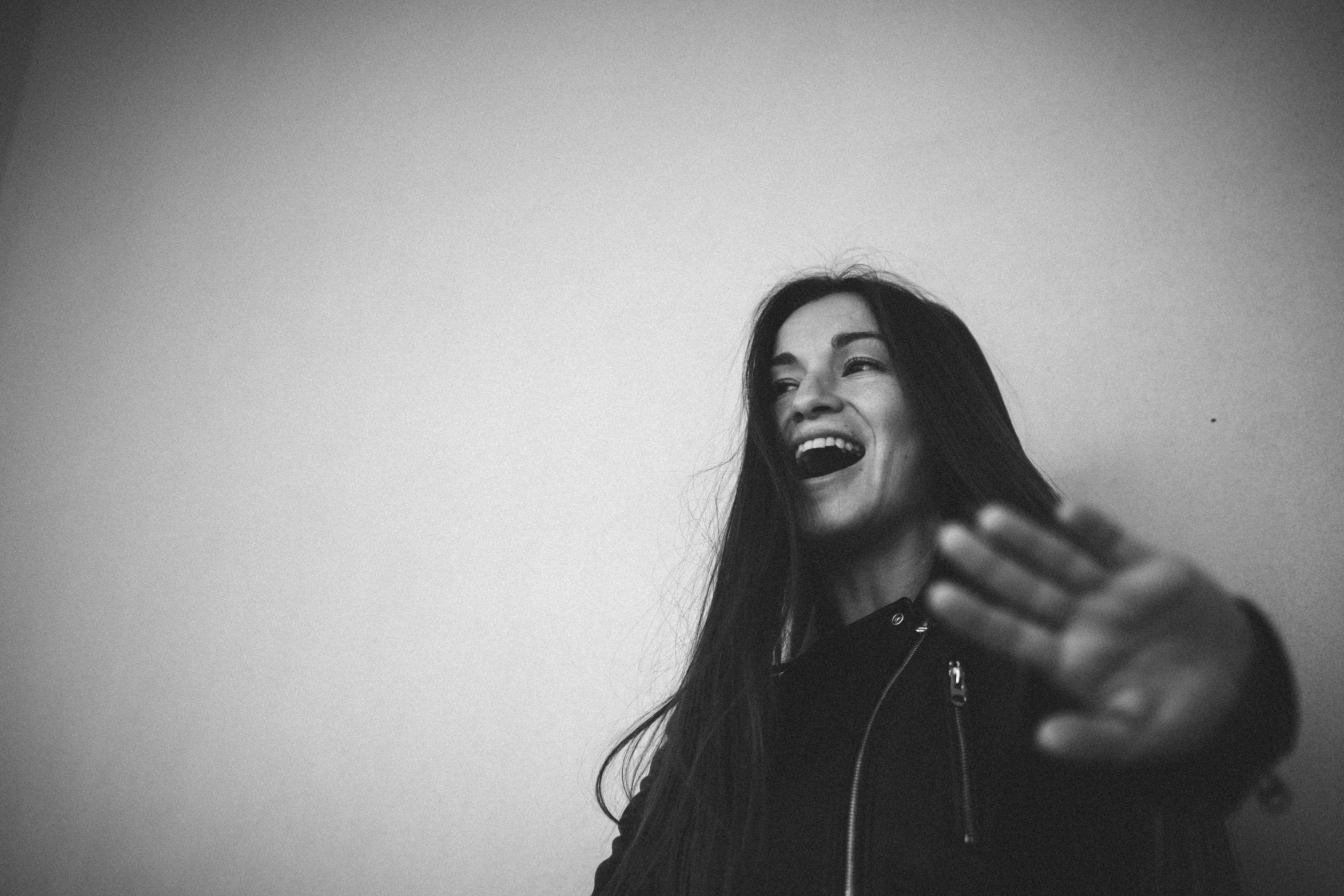 woman in black jacket looking up smiling and laughing