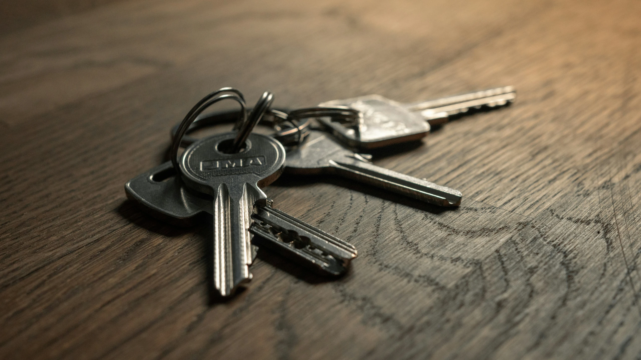 three keys sitting on top of a wooden table