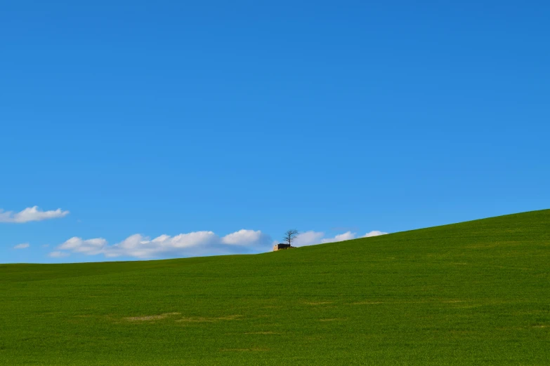 a small house is on the top of a grassy hill